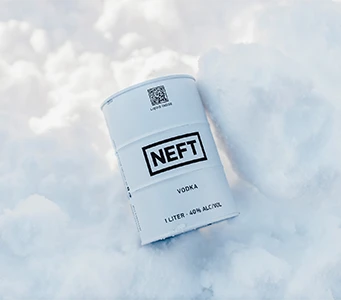 A NEFT Vodka white barrel laying in a pile of pure white snow.
