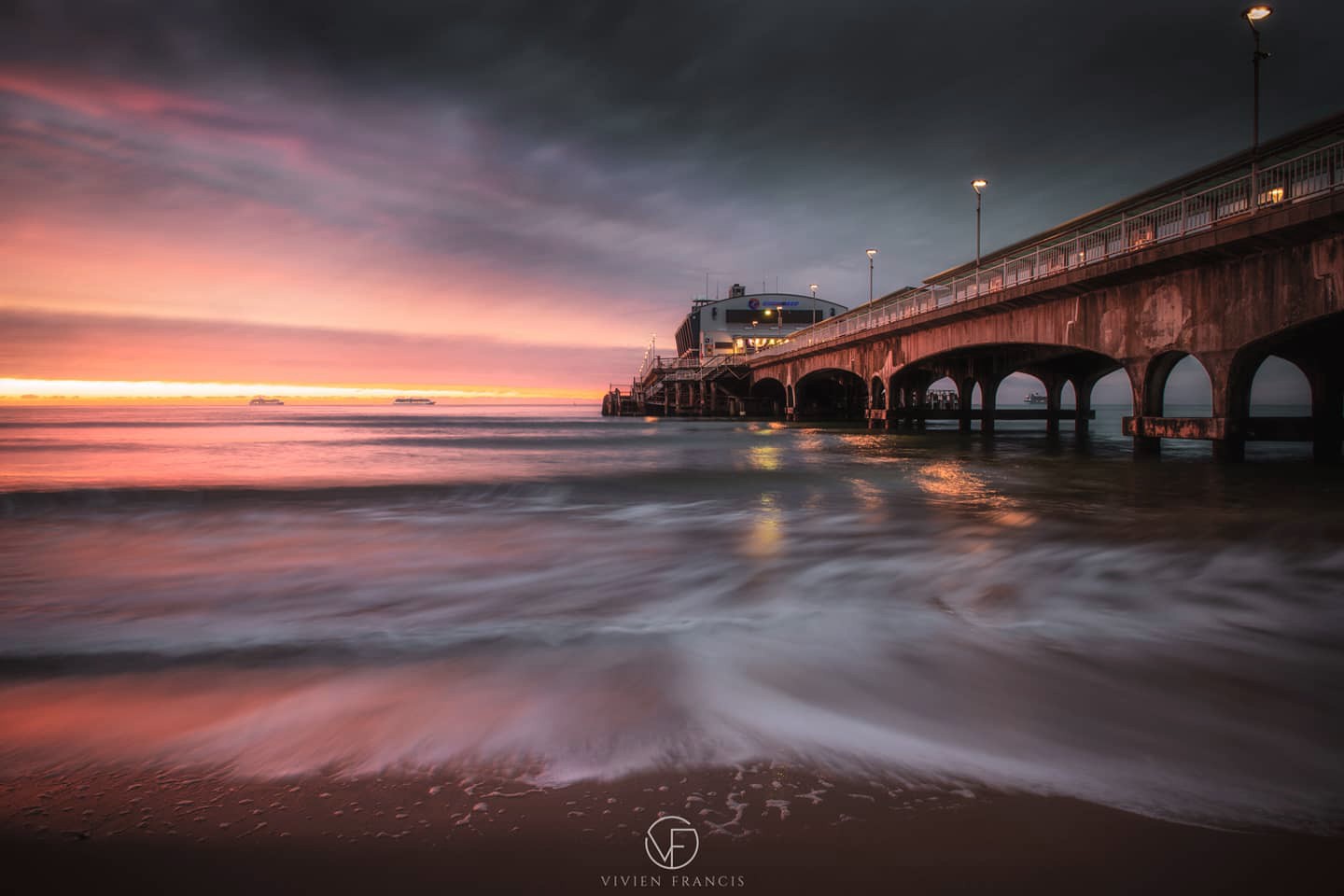 Pier on the shore with the sea rolling in and an epic sunset