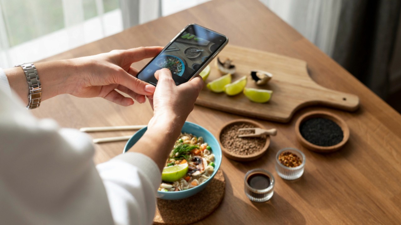 Woman taking photo of bowl of ramen and sliced lemon