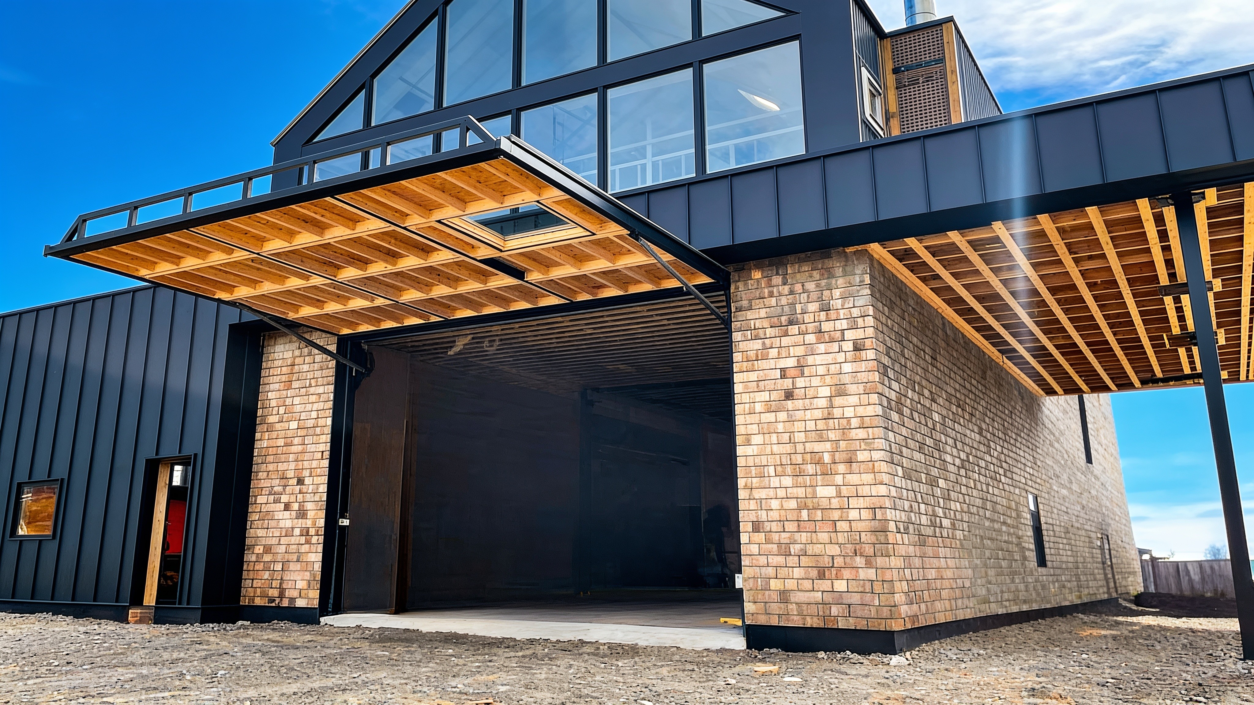 Coastal boat shed with black metal siding and an open PowerLift hydraulic door