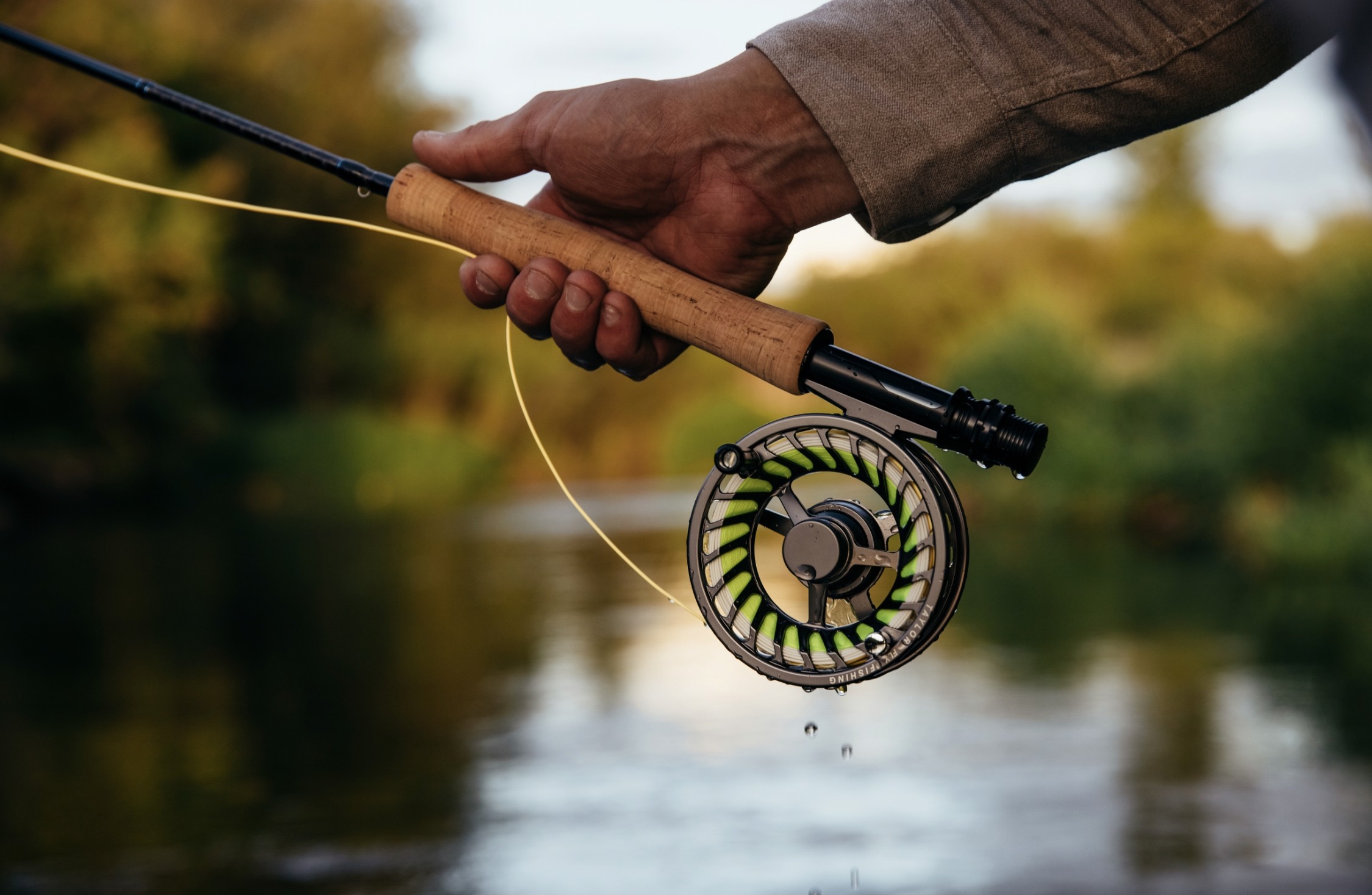 fly fishing rod and reel being held with natural background 