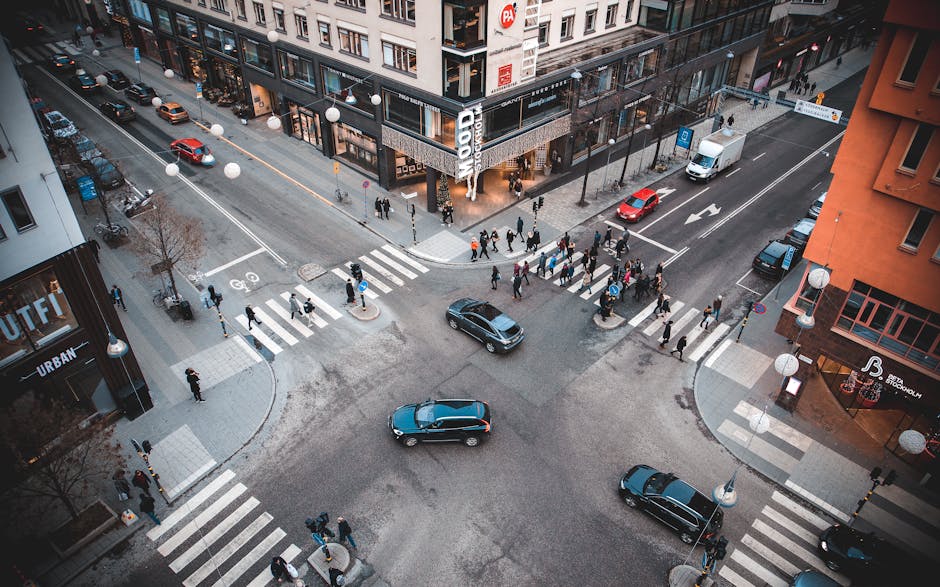 A bustling city intersection with pedestrians and vehicles on a sunny day.