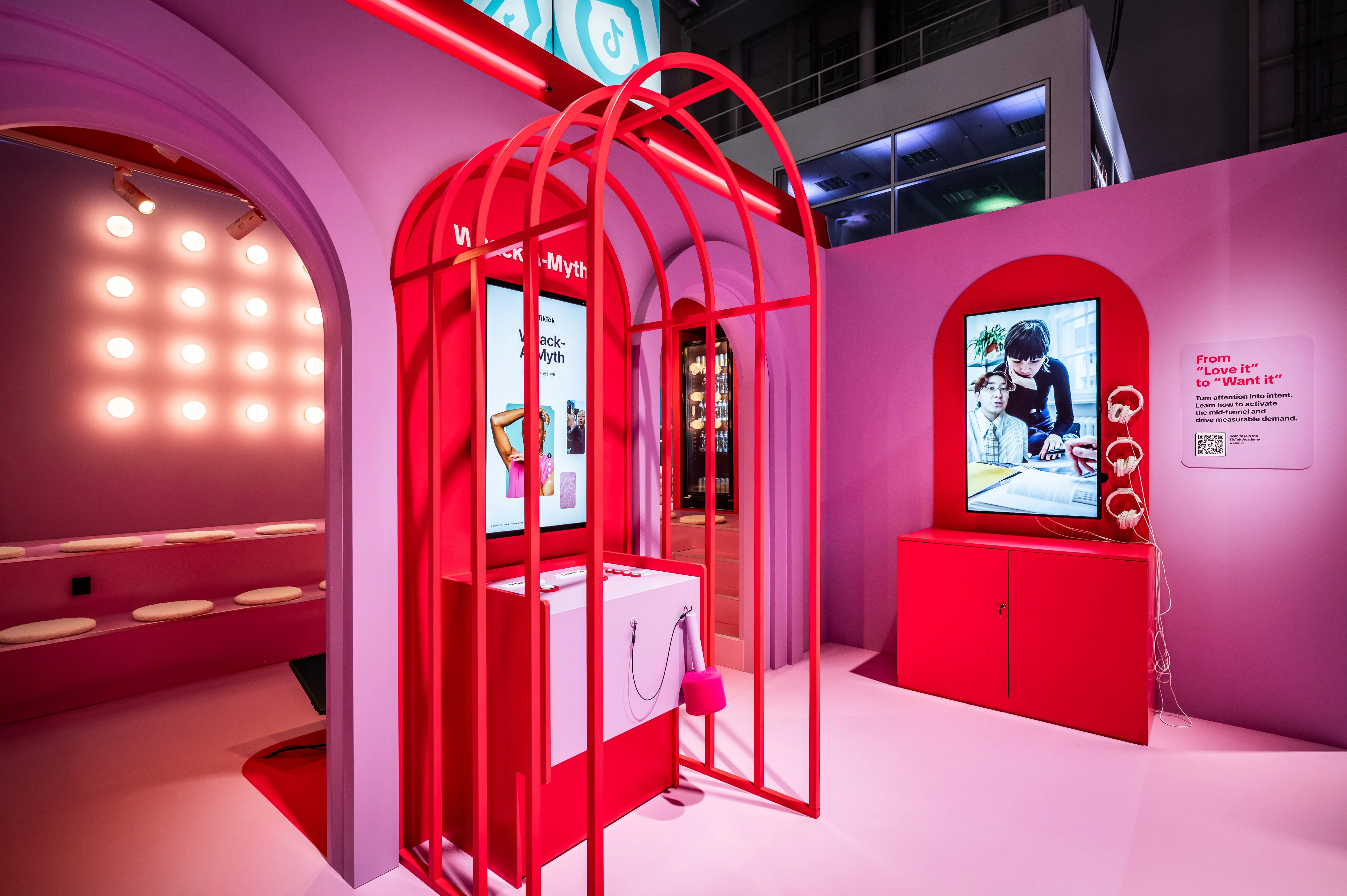 Pink zone with red arched cage installation, screens and make-up mirror lights at the TikTok booth.