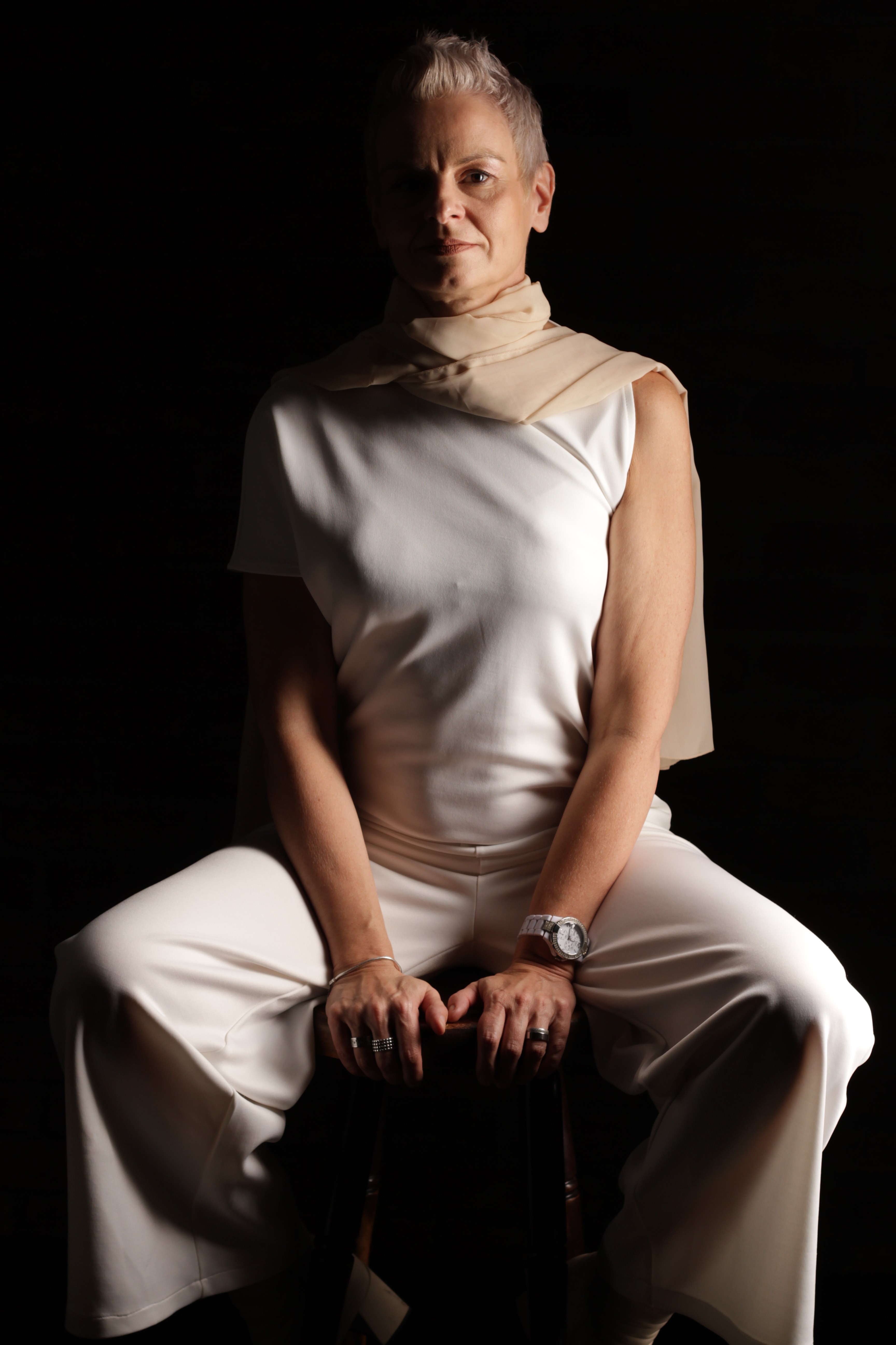 A thoughtful young person with dark hair gazes to the side, captured in soft black and white lighting.