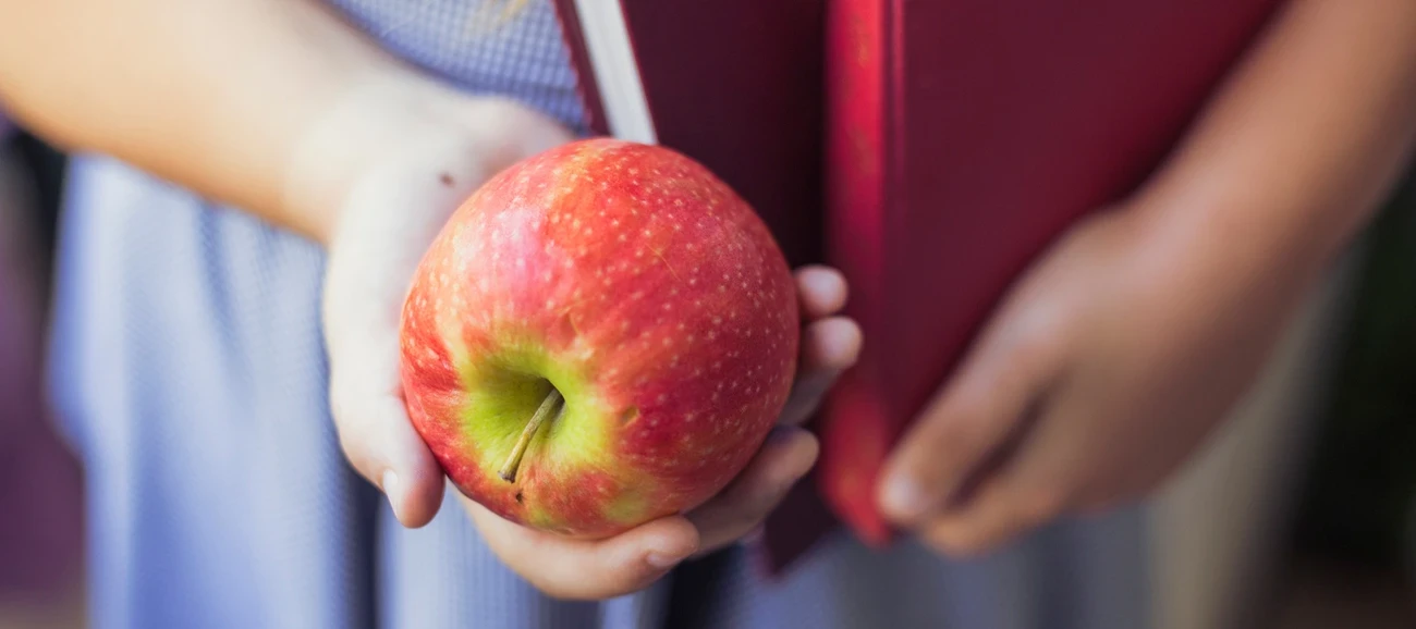 Enfant tenant une pomme dans sa main.