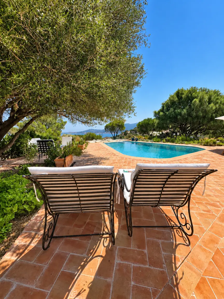 Piscine de San Damiano avec terrasse en terre cuite, deux transats et vue sur la mer entre les arbres