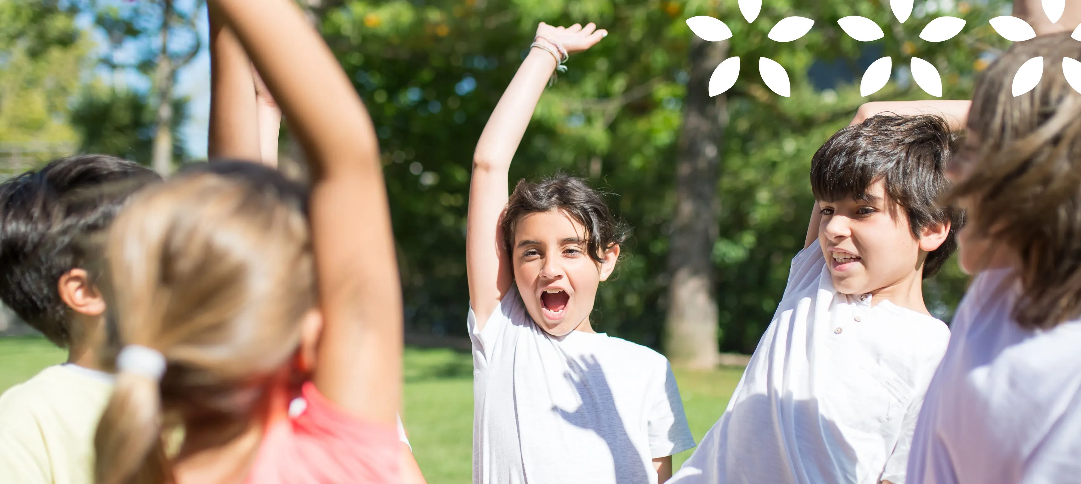 A group of kids huddled up and cheering on a field with 3 apple seed graphic elements overlayed in the top right corner.
