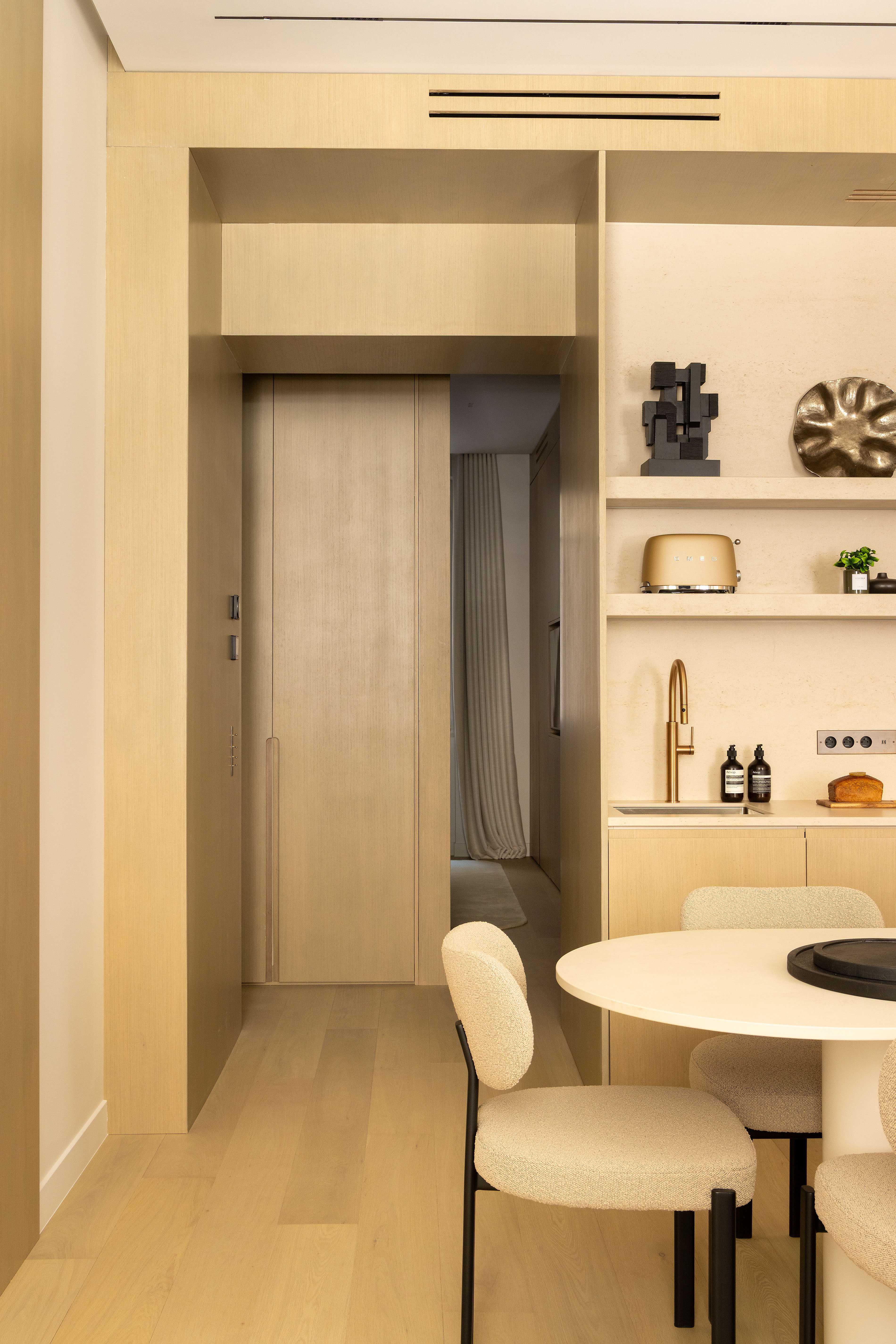 Angle cuisine montrant la porte coulissante vers la chambre et les étagères décoratives en bois