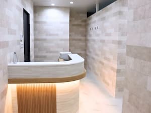 間接照明が心地よく灯る、大理石調の床と木目が美しいBEAUTY SALON eightの受付カウンター