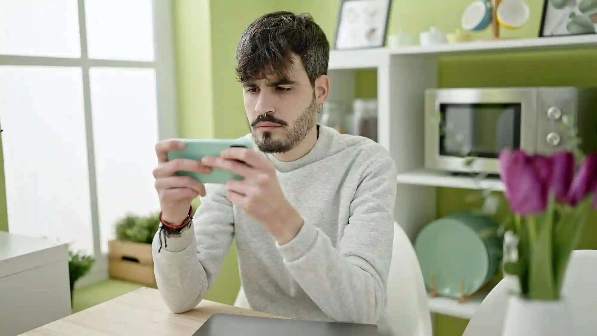 A focused man uses his smartphone horizontally, likely viewing or editing content for a campaign.