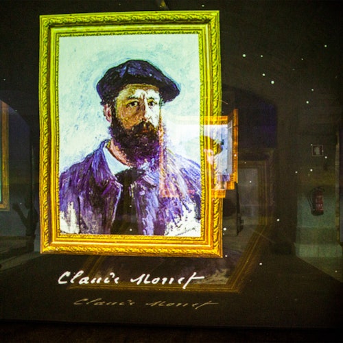 Nakapuwesto ang naka-frame na larawan ni Claude Monet laban sa madilim na background na may kanyang pirma sa ilalim.