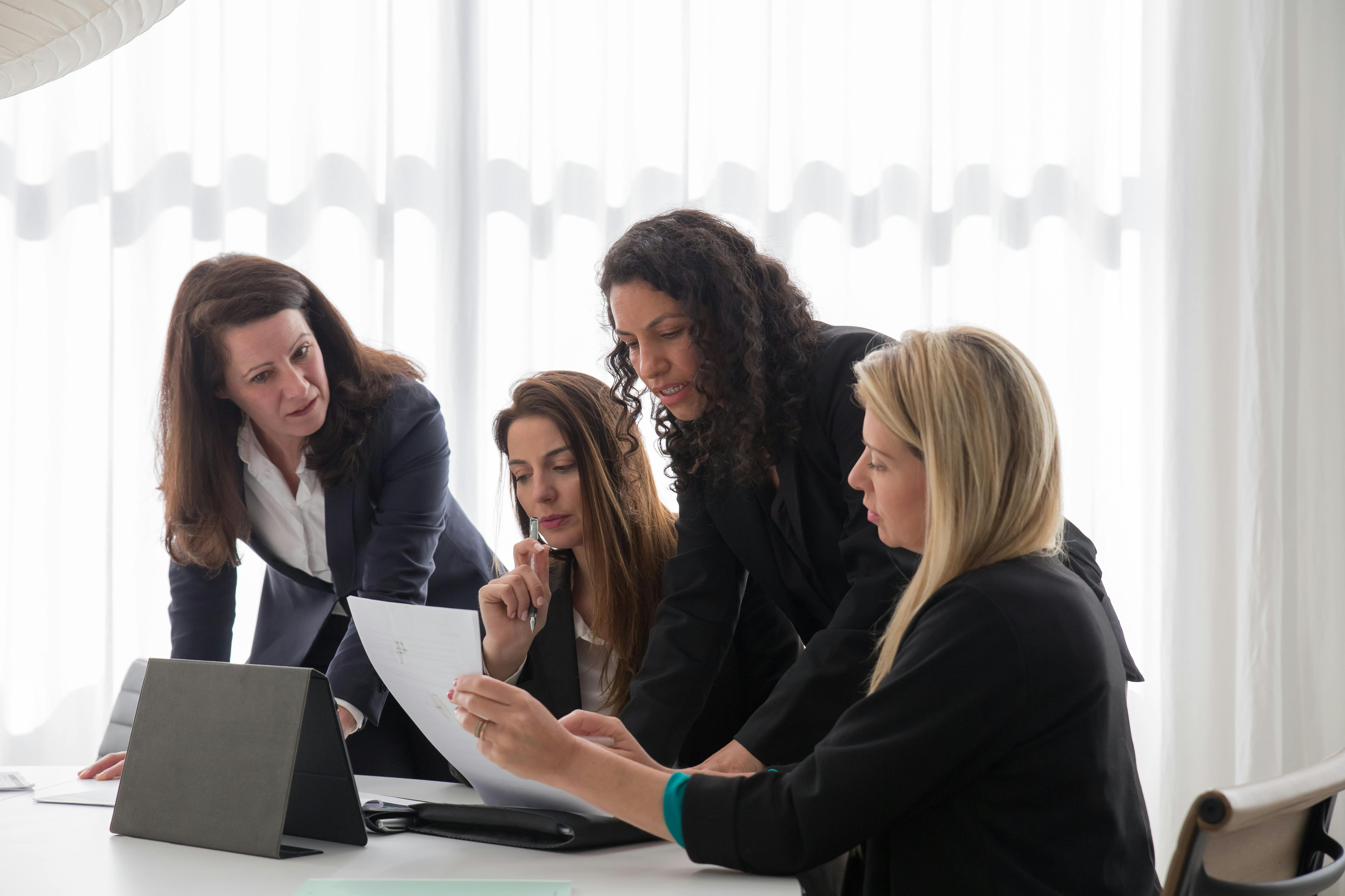 Team femminile in riunione con tablet e documenti: strategia e project management