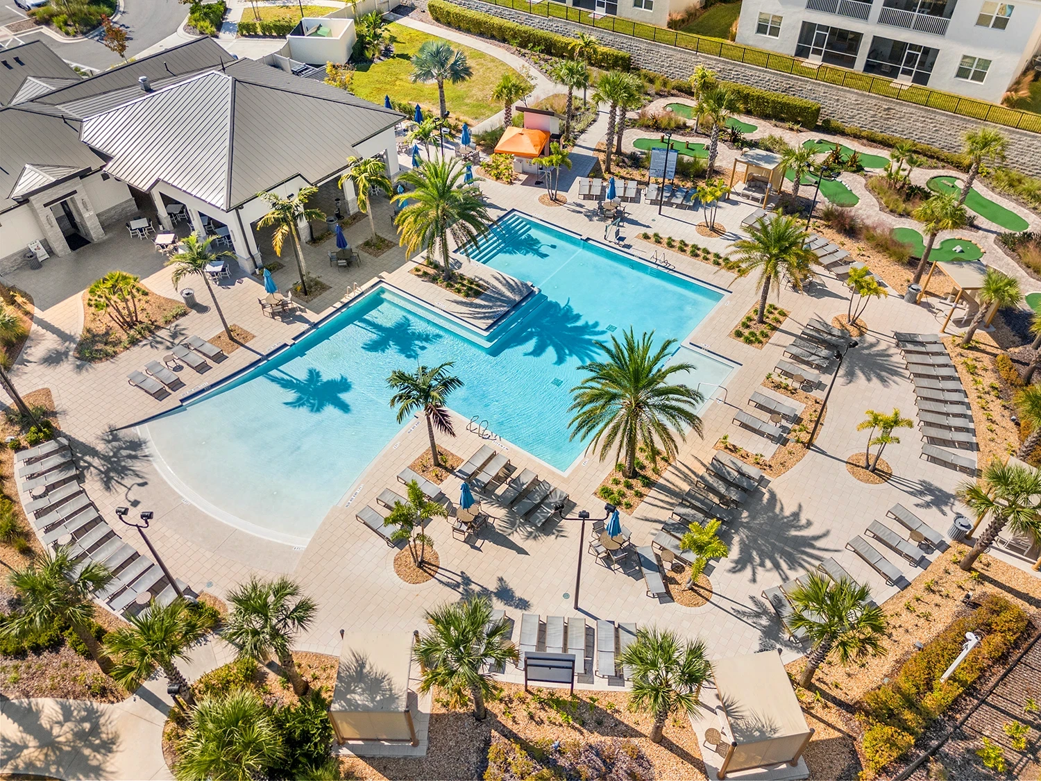 Aerial photo of the ChampionsGate community pool with large swimming areas, sun loungers, palm trees and cabanas