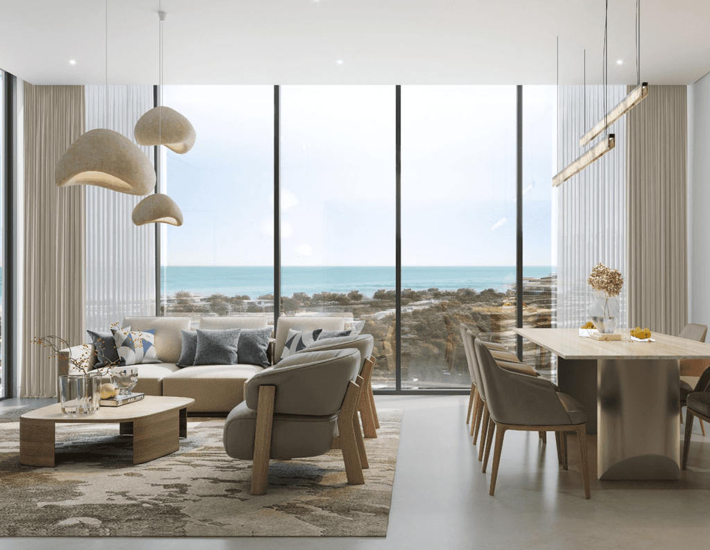 A modern living room featuring large windows with a stunning view of Delphine Beach and the ocean beyond.