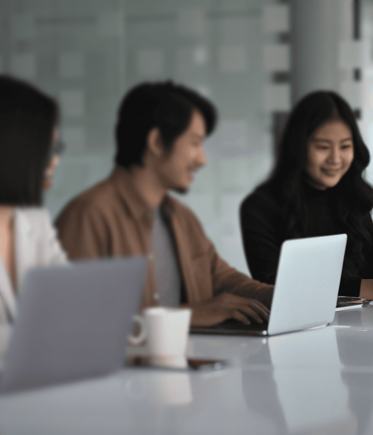 A diverse group of professionals collaborating at a table with laptops and a coffee cup.