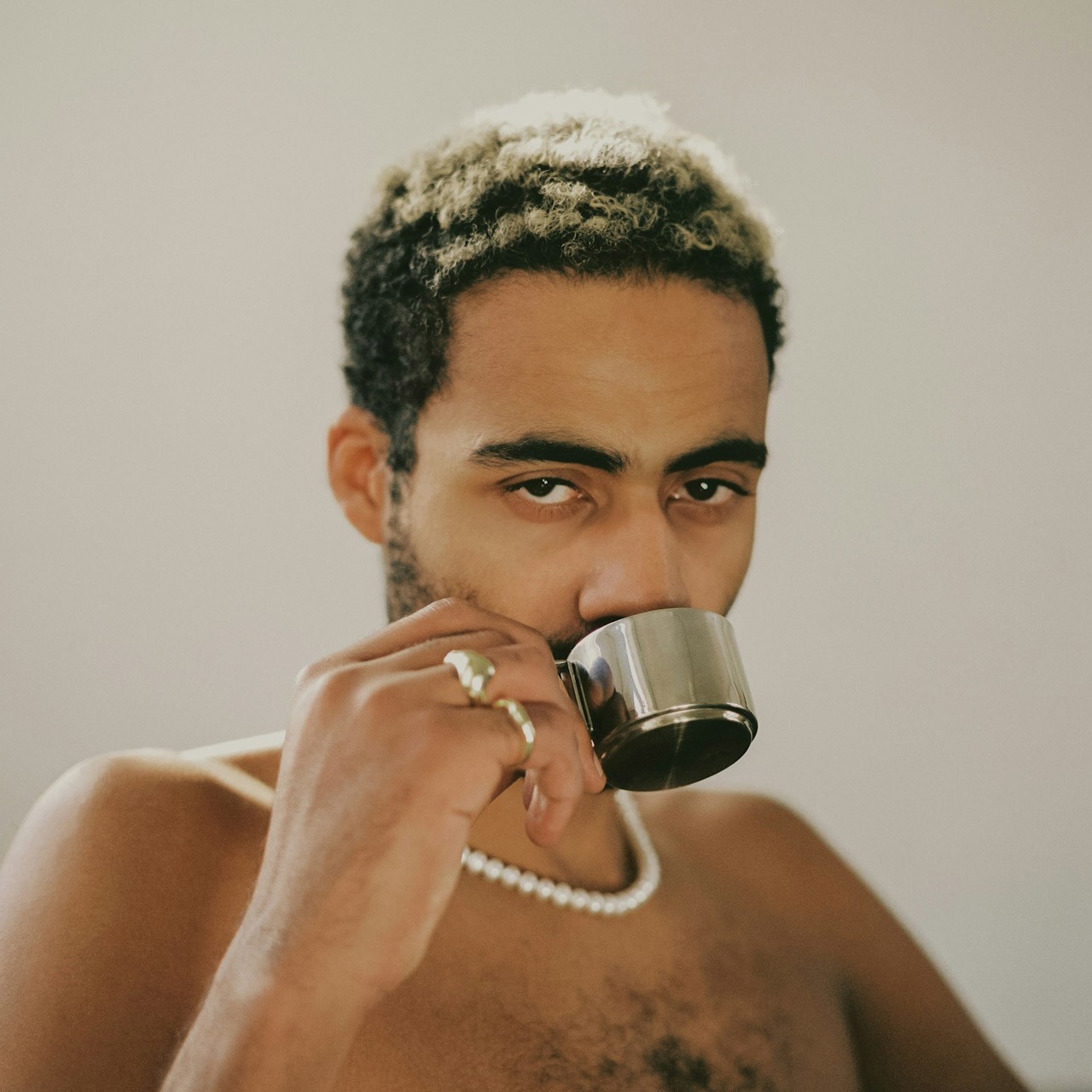 Shirtless man sipping espresso