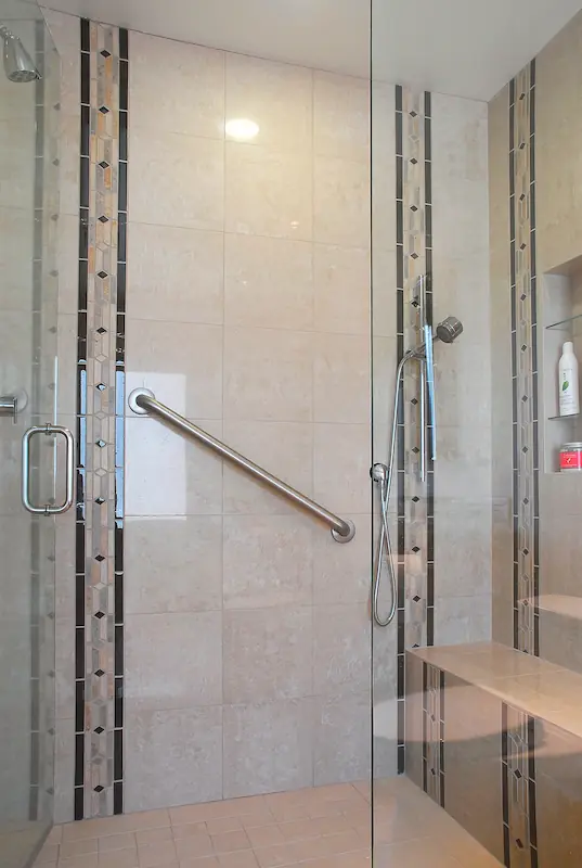 Glass shower enclosure with beige tiles and decorative inlay in Irvine Transitional Modern. Photo by Chris Darnall.