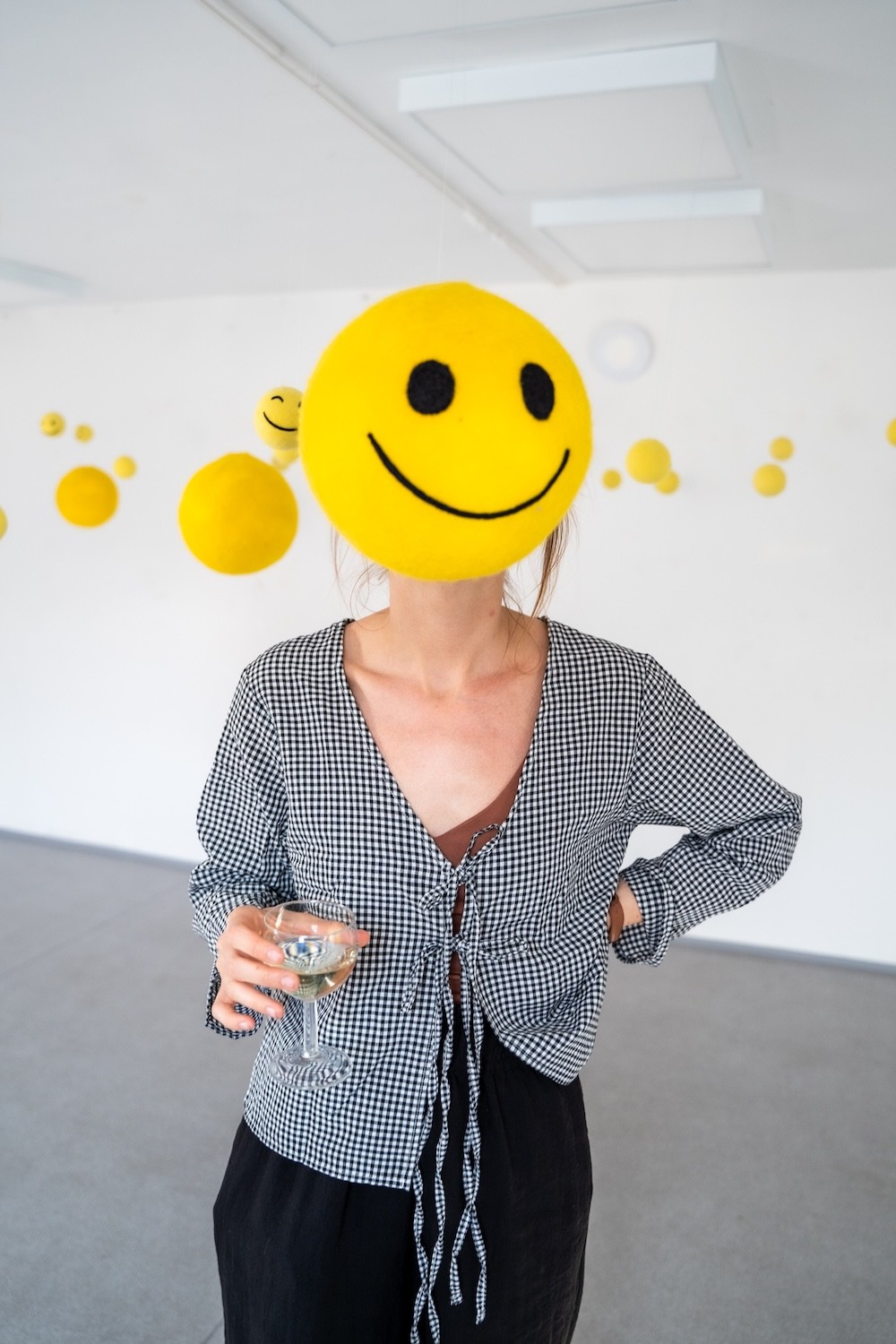 žltý smiley objekt visiaci v priestore pred človekom – výstava Niny A. Šoškovej