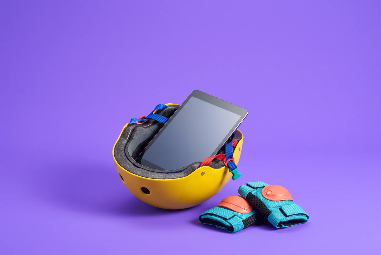 A tablet in a kids' bike helmet with knee pads, setting up devices when you talk to your son about porn