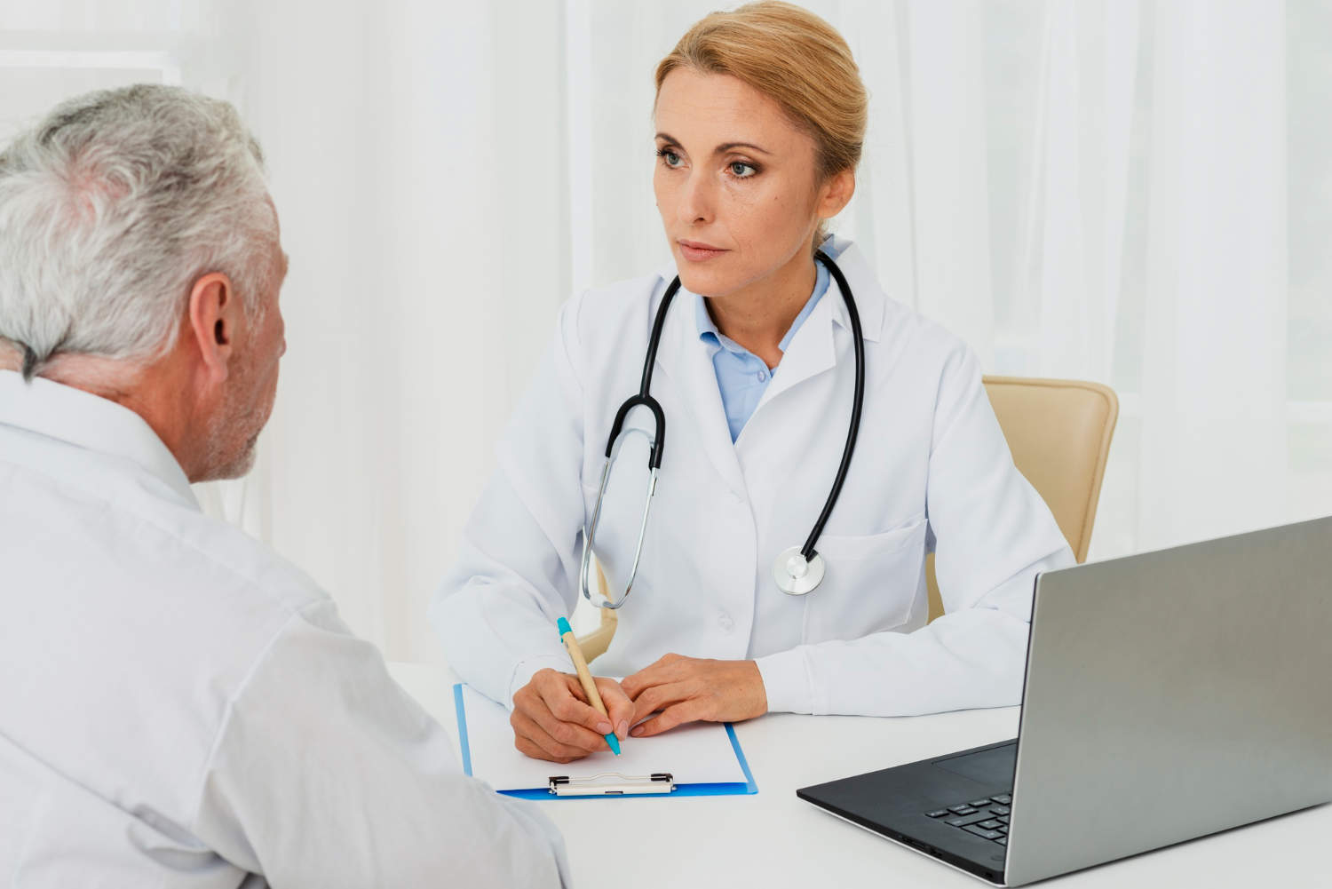 A female doctor conversing with a male patient during a medical consultation.