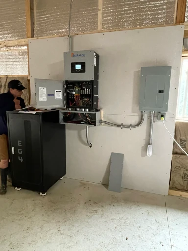 Residential battery backup system with a Sol-Ark inverter, EG4 battery cabinet, and electrical panel during installation.