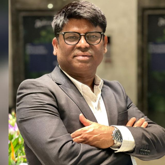 A businesswoman sitting at her desk, smiling and looking at the camera.