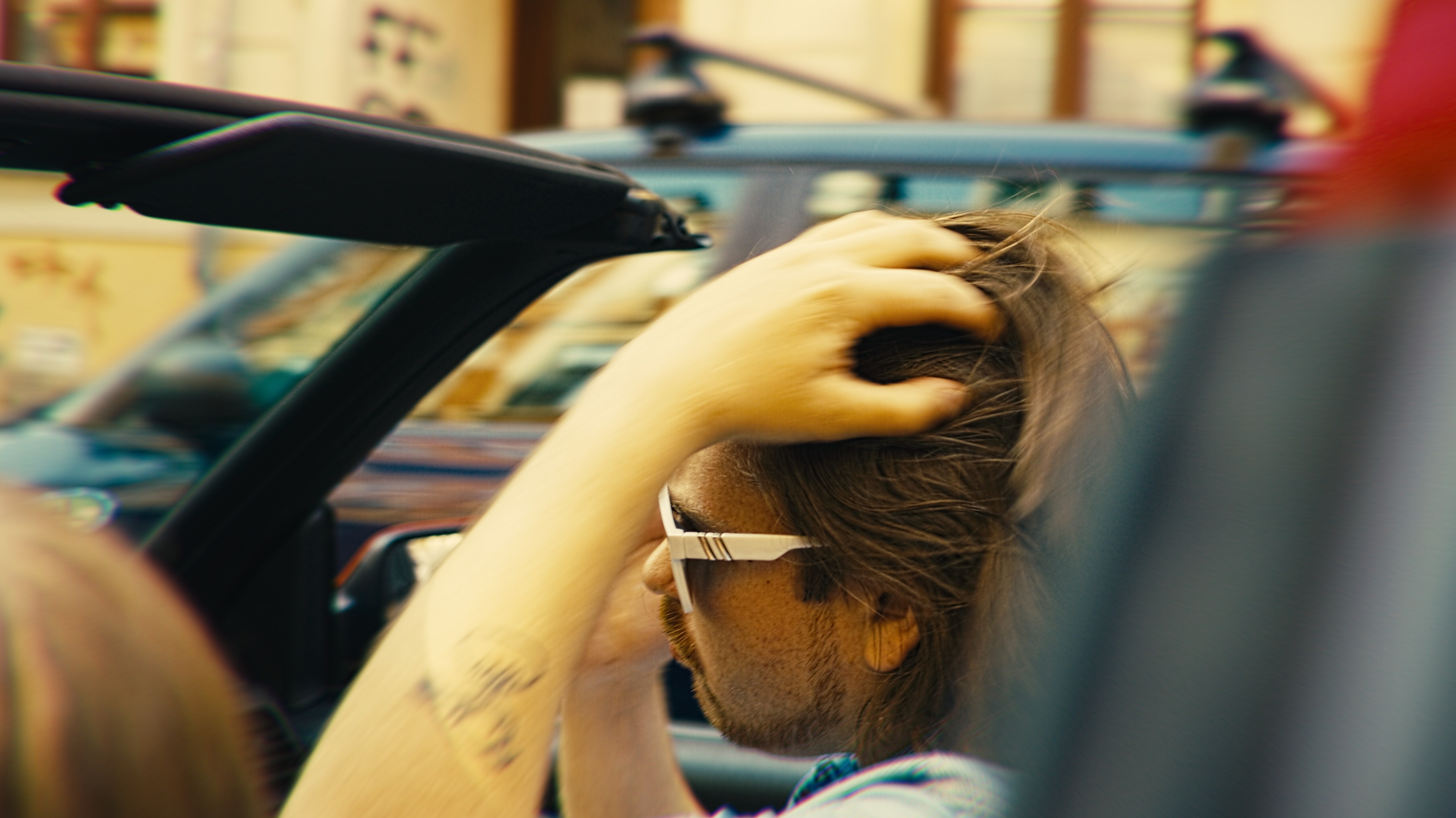 Mann sitzt im Auto, fährt sich durch die Haare