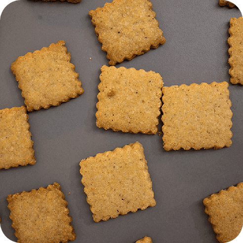 Galletas especuloos artesanales distribuidas sobre superficie gris.