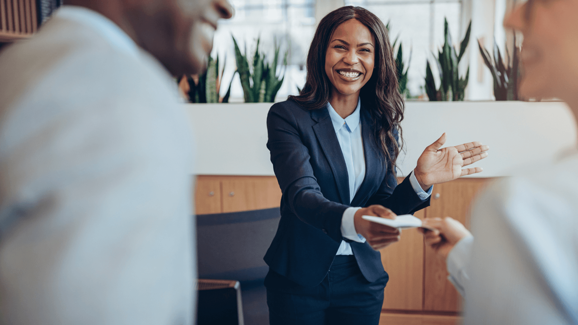 A smiling, confident-looking woman in a professional business attire, likely in an office or workplace setting. Her warm and engaging expression conveys a sense of positivity and approachability.