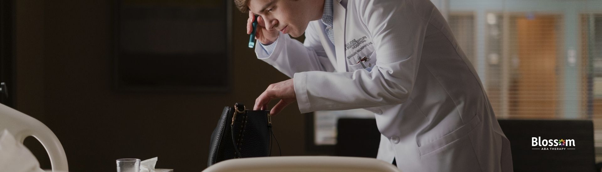 Dr. Shaun Murphy from The Good Doctor series listening intently on a phone in a hospital room.