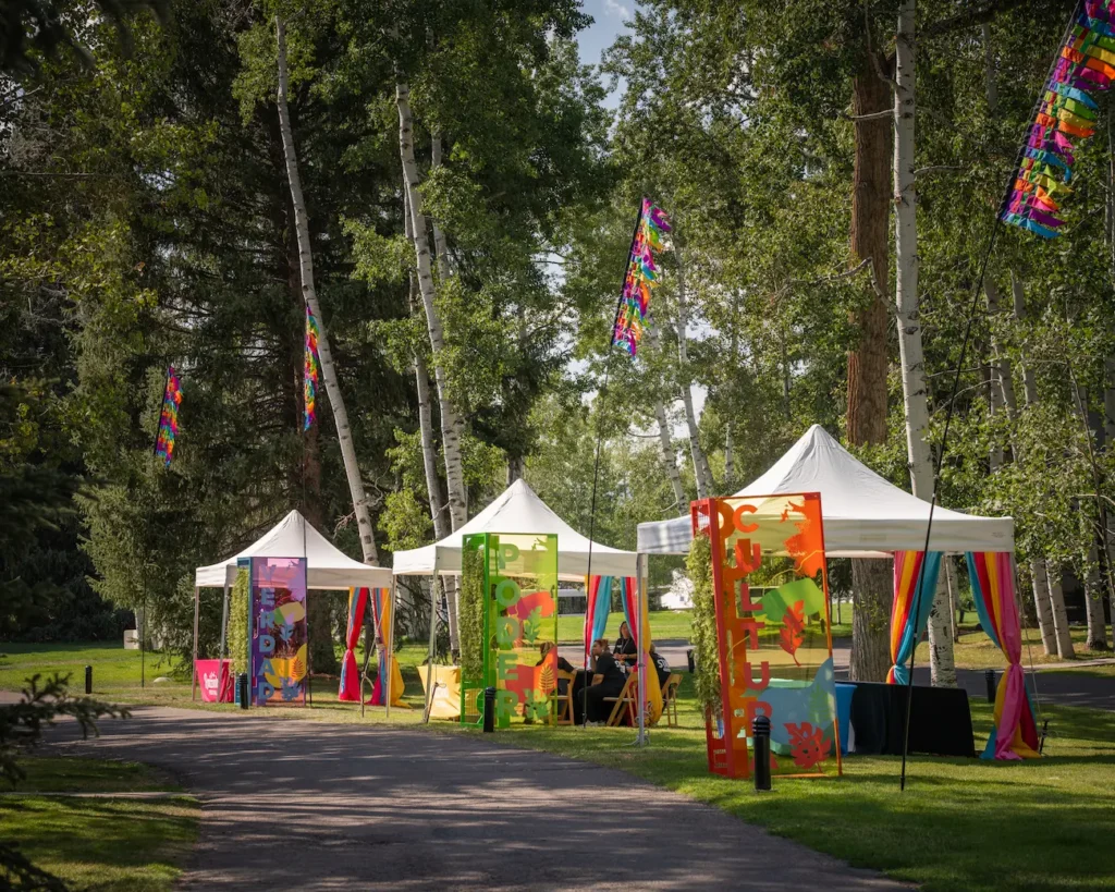 Colorful festival booths arranged beneath tall trees