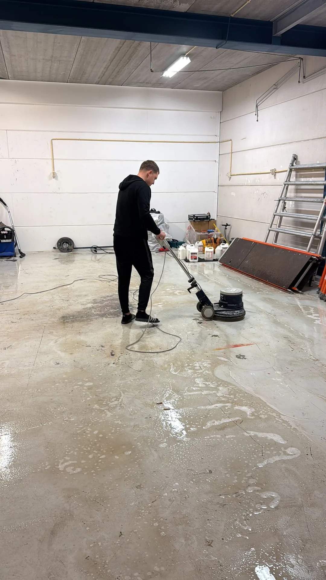 Medewerker van Qlean Facility Group behandelt de vloer van een bedrijfsruimte met een boenmachine