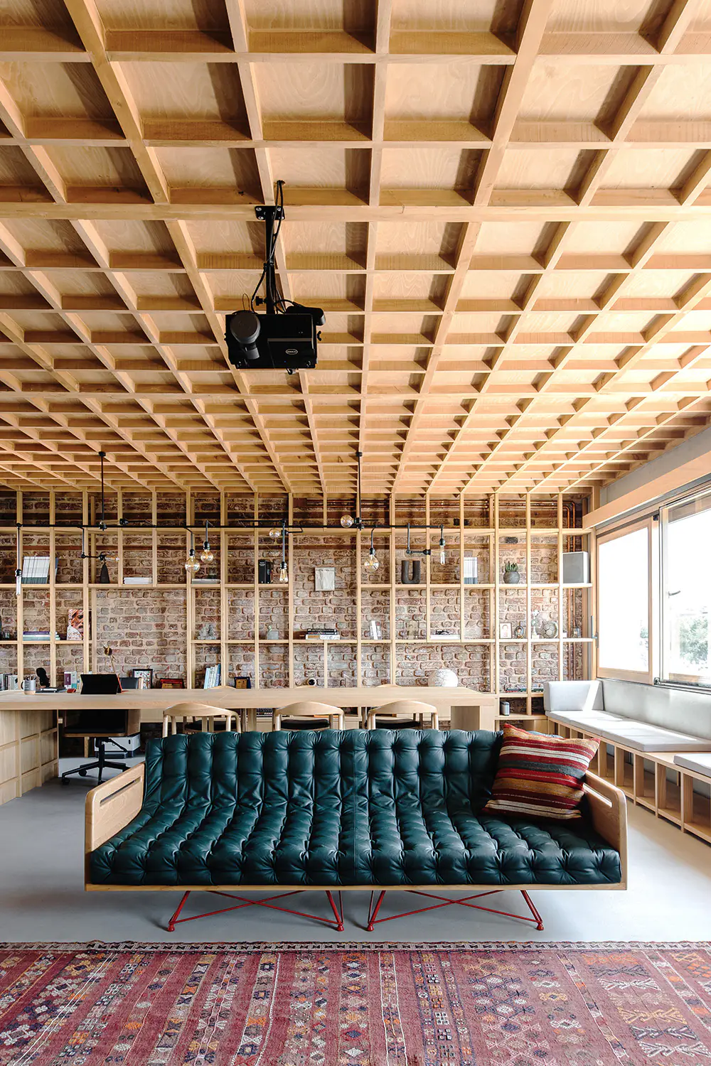 Green leather sofa and kilim rug in front of the library wall