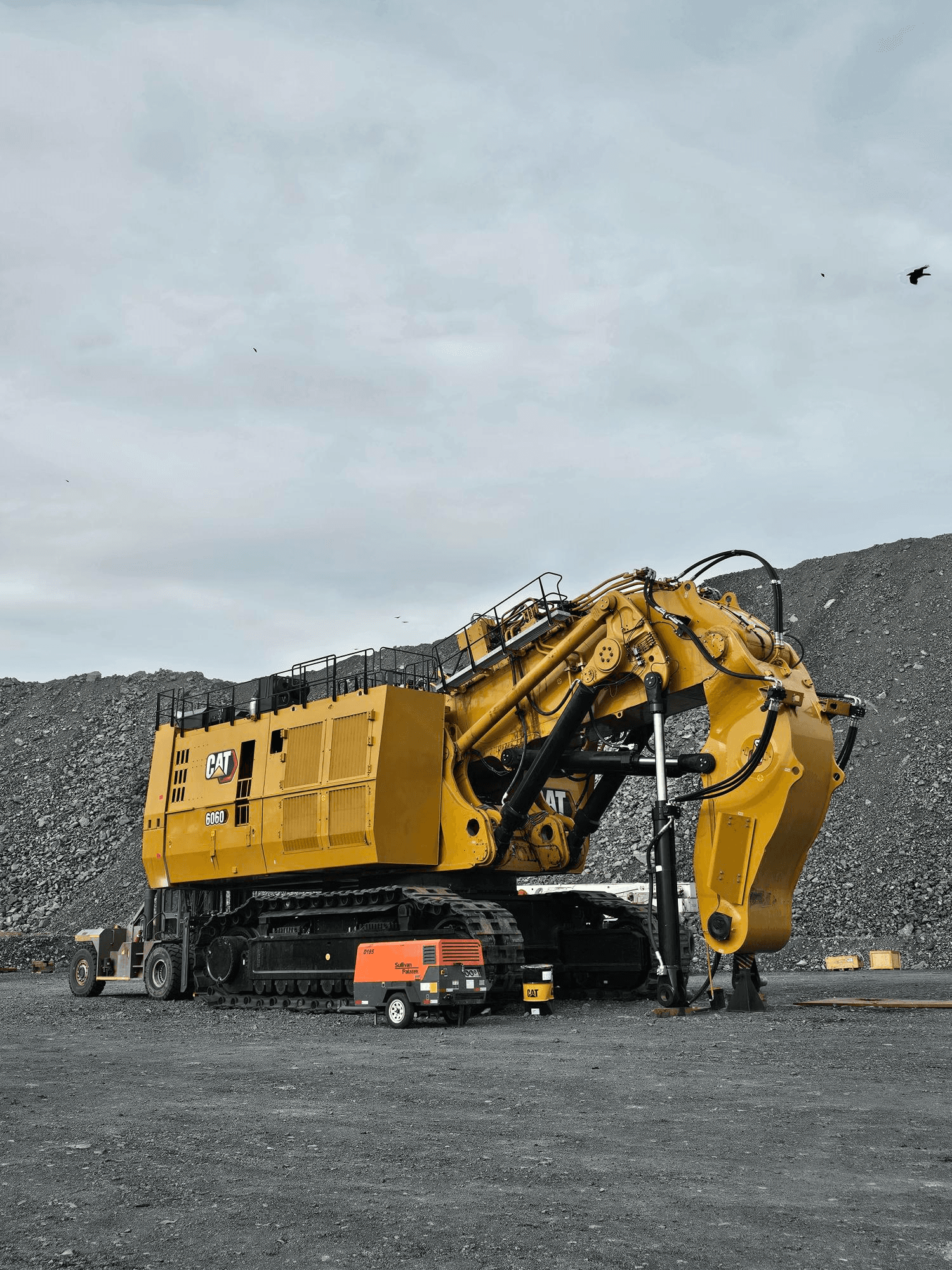 Aerial view of a hydroelectric dam spanning a turquoise river surrounded by dense forest and winding roads