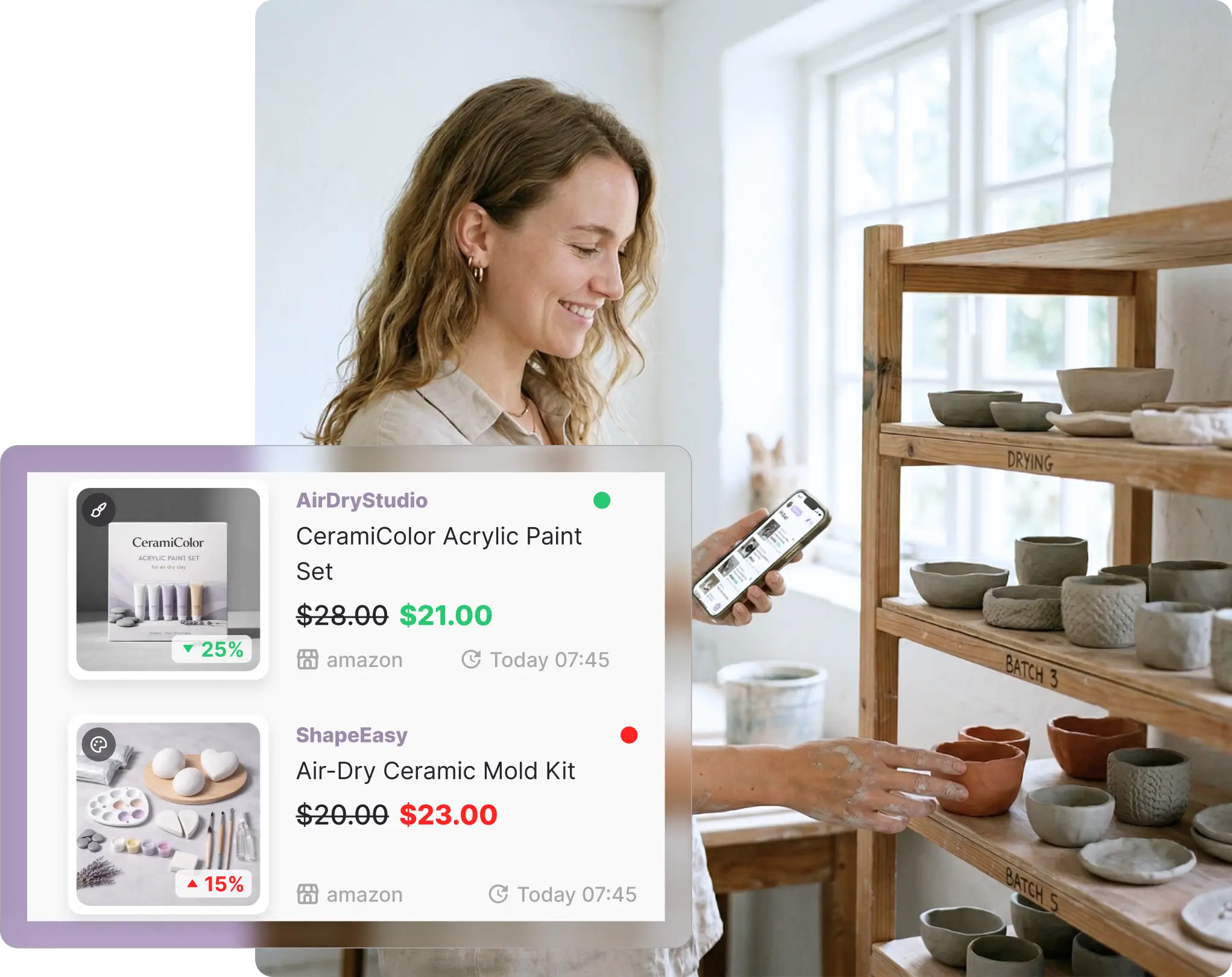 A smiling woman working in a bright pottery studio, holding her smartphone in one hand while arranging handmade ceramic bowls on a rustic wooden shelving unit. Overlaid on the scene is a Whisprice digital interface mockup showing tracked Amazon items: a "CeramiColor Acrylic Paint Set" from AirDryStudio marked down from $28.00 to $21.00, and an "Air-Dry Ceramic Mold Kit" from ShapeEasy marked up from $20.00 to $23.00.