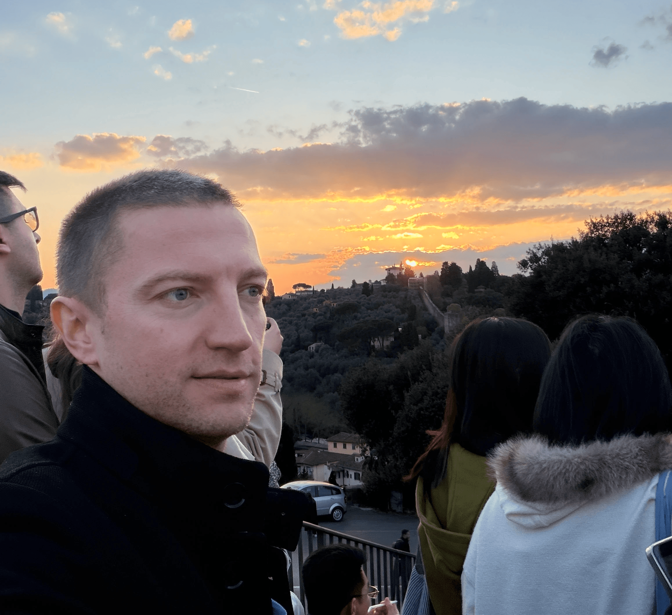 Ivan, Founder of Booscala, looking towards a scenic sunset over hills.