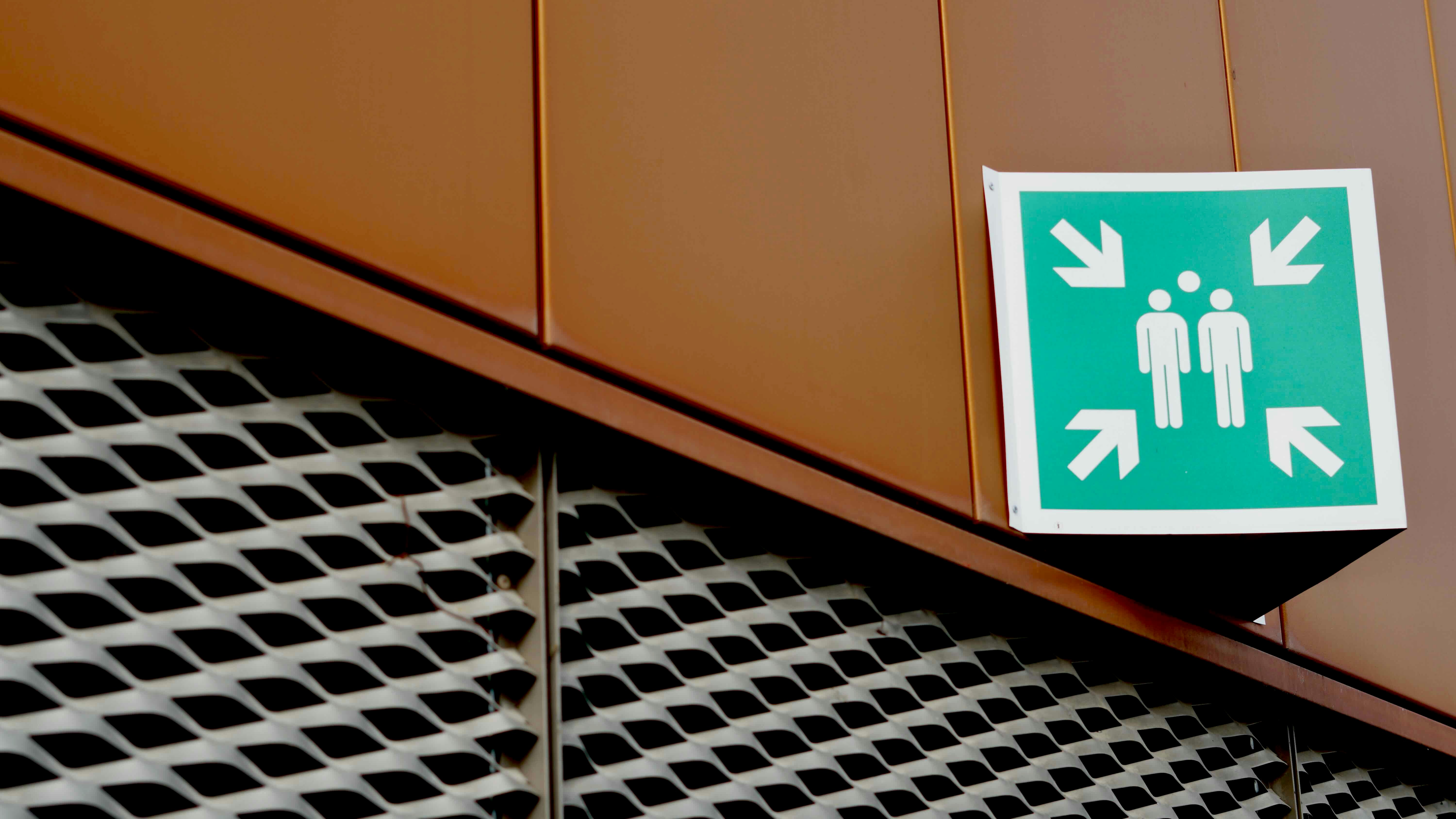 Green emergency assembly point sign on building