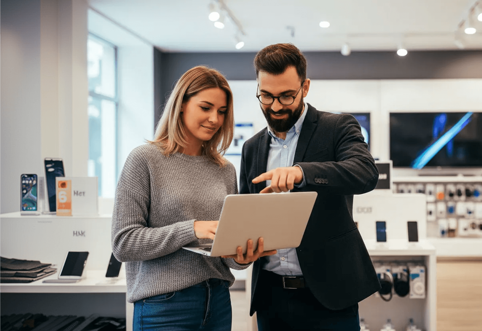 Two professional retail consultants collaborating over a laptop in a modern showroom.