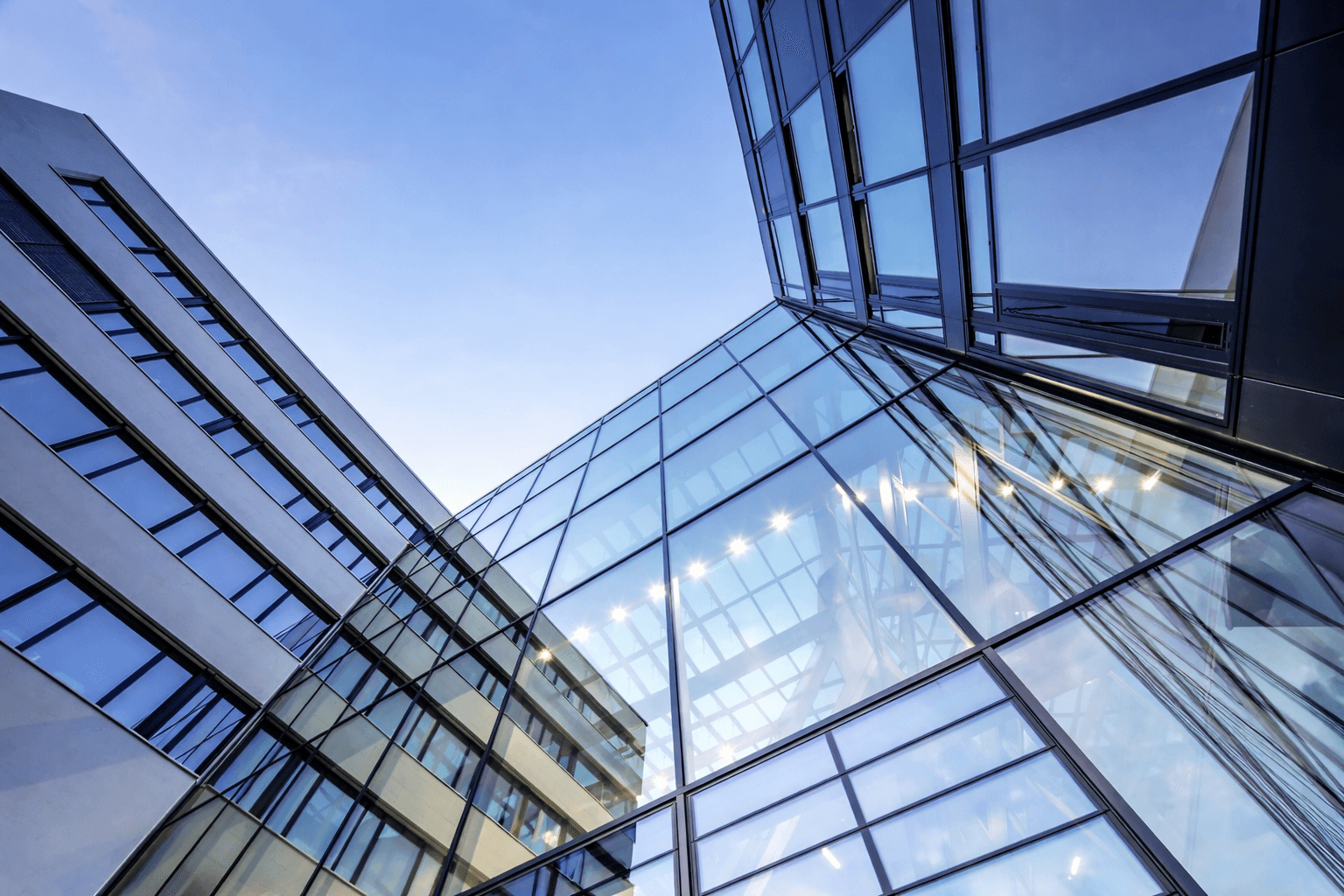 Blick nach oben auf moderne Glasfassaden eines Bürogebäudes.