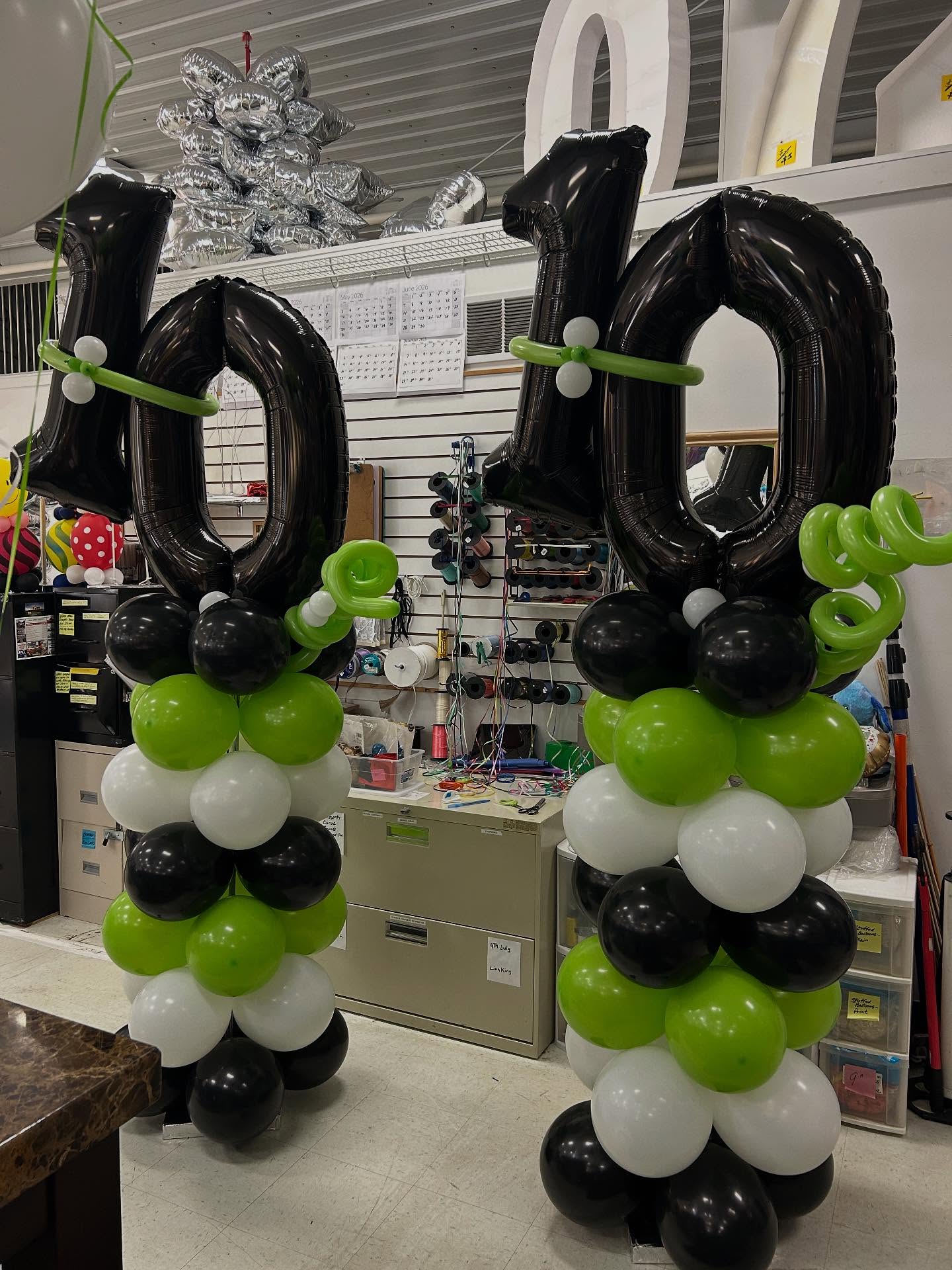 Pair of tall black, green, and white balloon columns with number 40 toppers displayed indoors by Be Bold Balloons