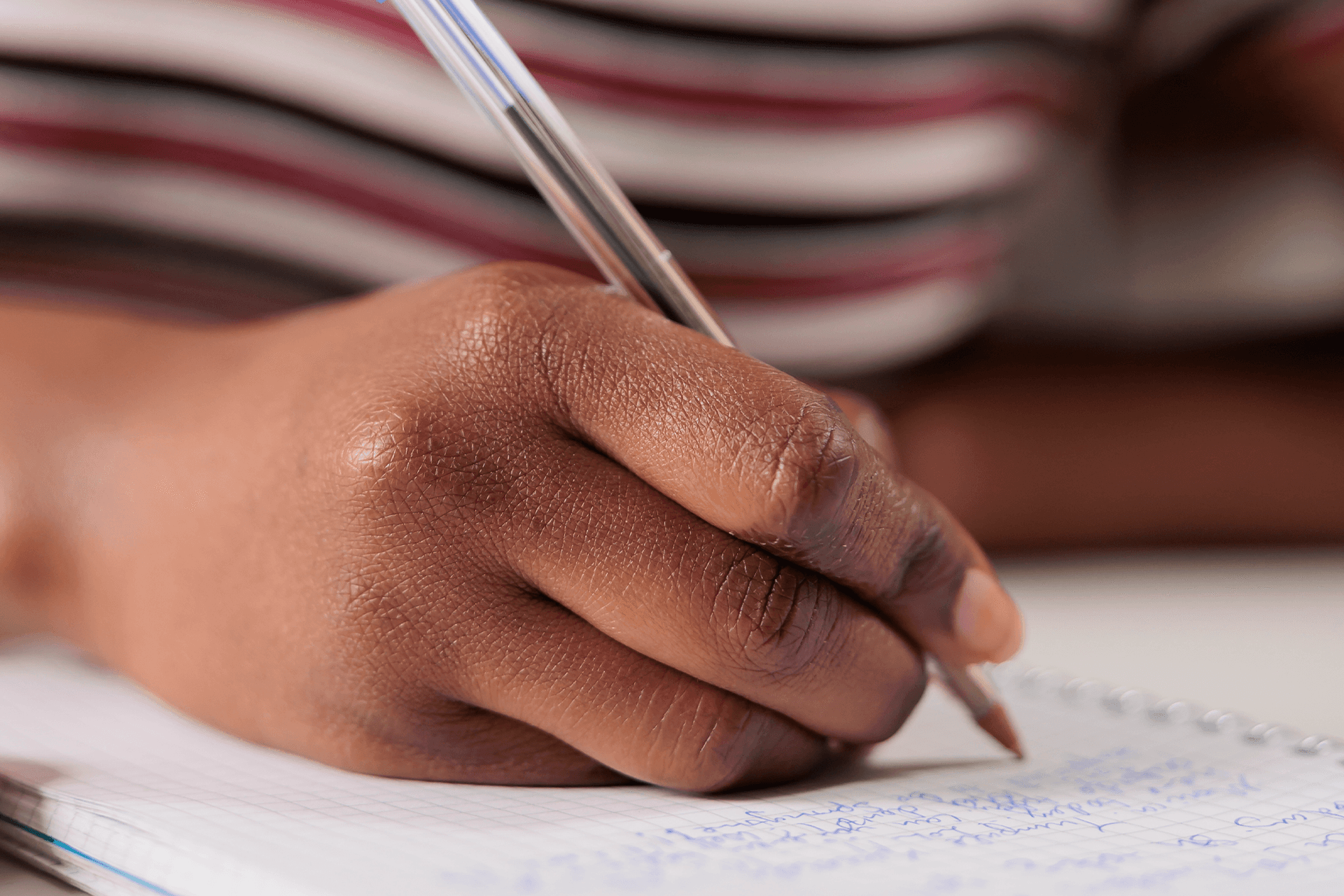 Close-up of a hand writing with a pen in an open notebook