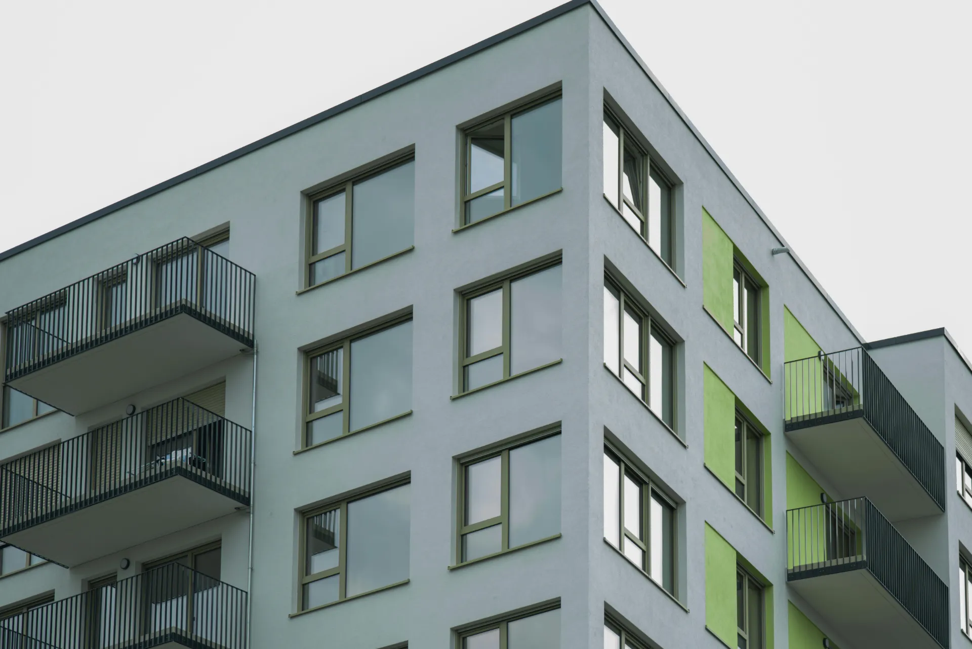 Ein Mehrfamilienhaus von der Seite fotografiert mit mehreren Fenster und Balkons.