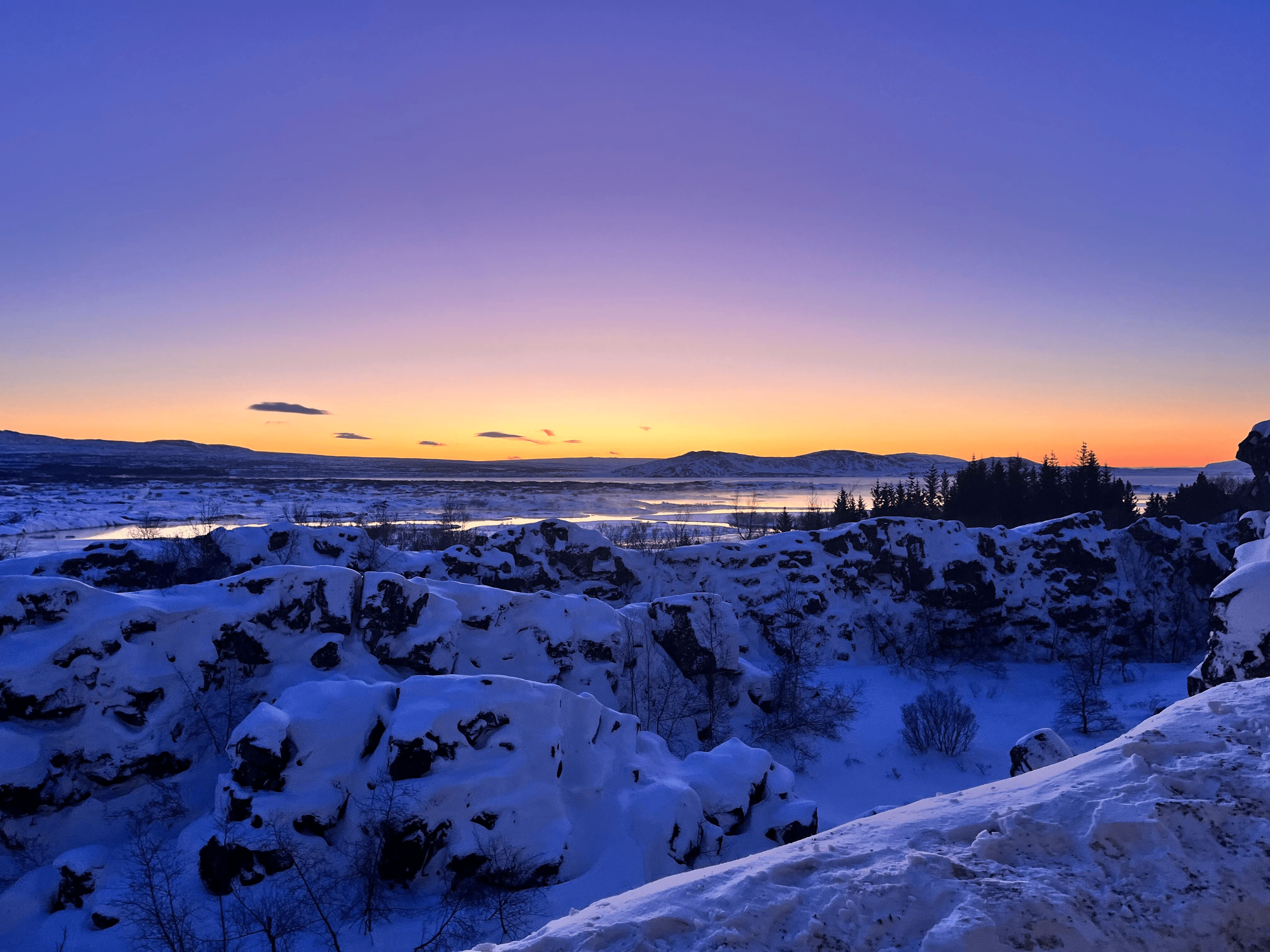 A snowy canyon landscape at sunset with dramatic lighting.