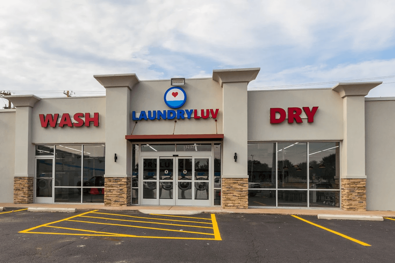 Front exterior of Laundry Luv at 3202 N. First Street in Abilene, Texas, featuring the red and blue Laundry Luv signage, “Wash” and “Dry” lettering, and the main storefront entrance.