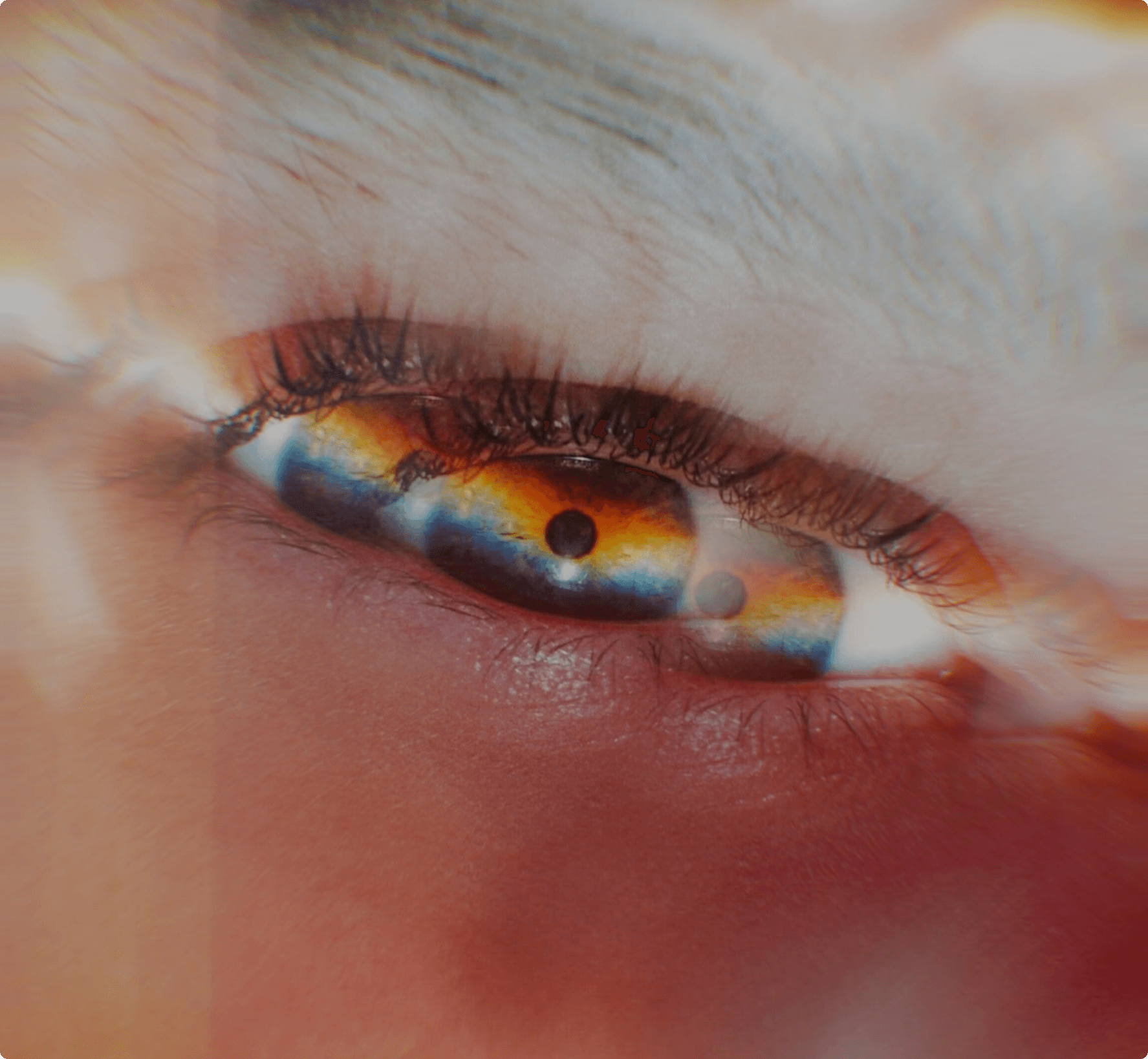  An extreme close-up of a human eye with a dreamlike, prismatic light effect creating rainbow colors across the iris and lens flare around the edges