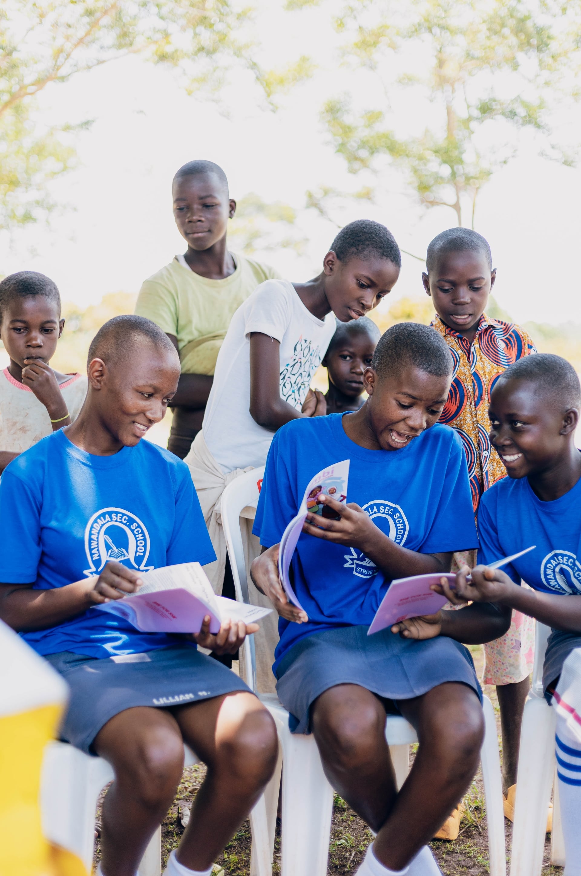 Students smiling while reading the Nambi the Menstruation comic book by SHE FOR SHE.