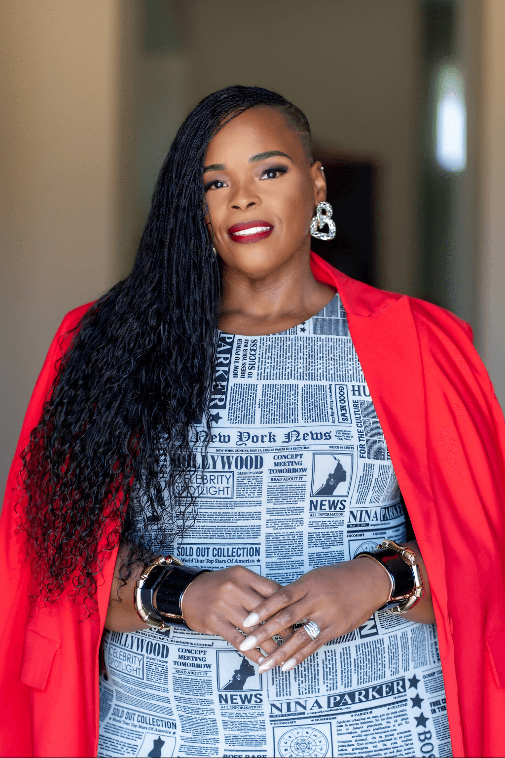 Kay Matthews, founder of the Shades of Blue Project, wearing a red blazer and newspaper-print dress.