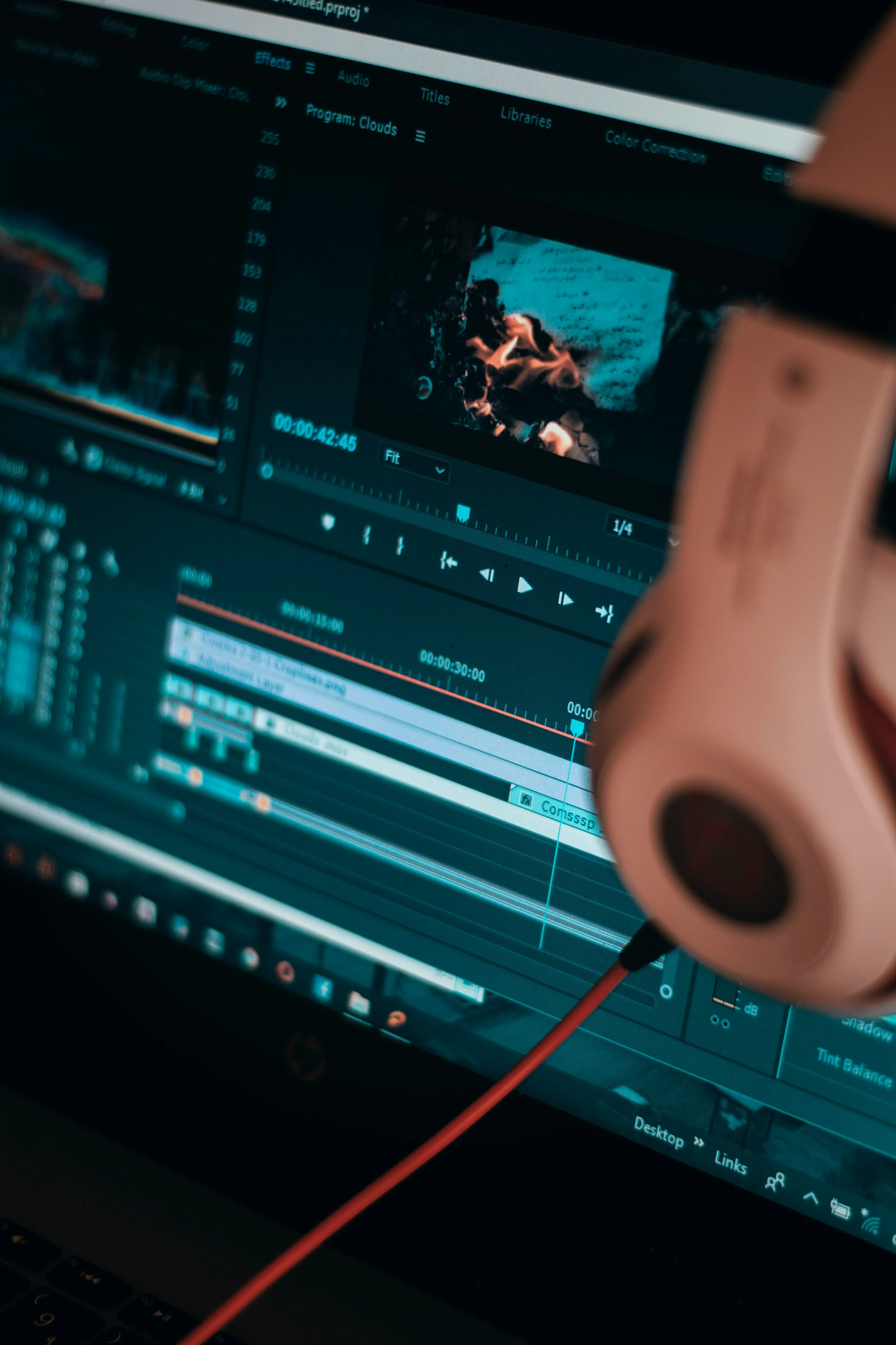 Picture showing a video editing software and headphone placed on the monitor