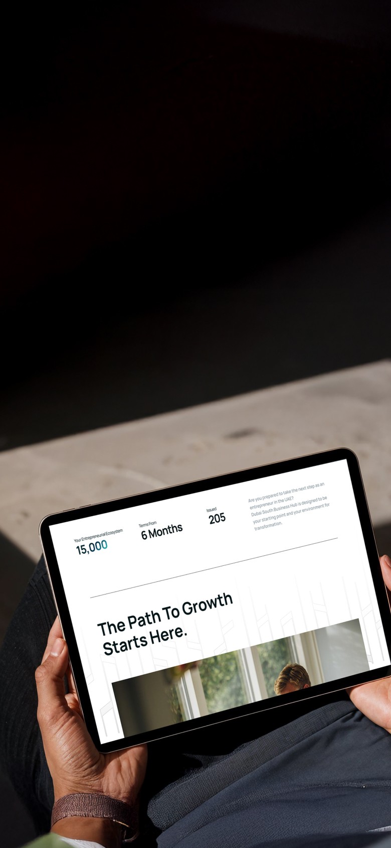 Dubai South Business Hub Free Zone -Person holding a tablet with the text "The Path to Growth Starts Here".