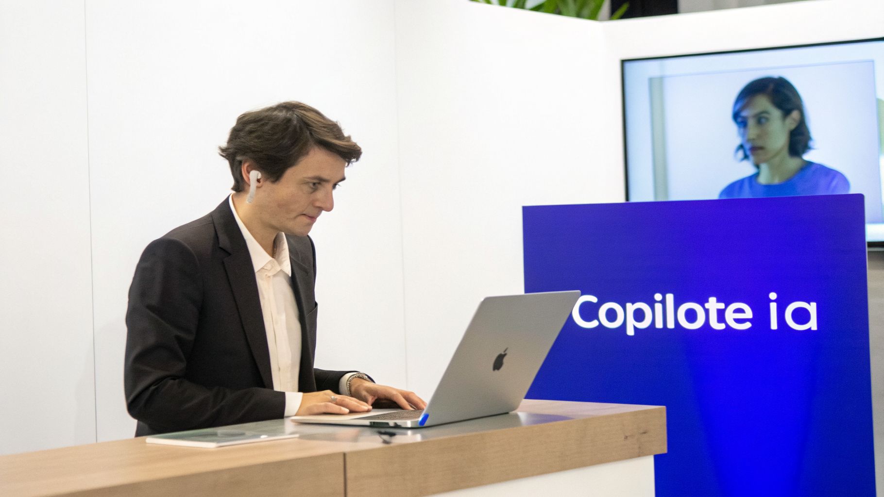 Homme en costume travaillant sur un ordinateur portable, avec un écran affichant 'Copilote ia' en arrière-plan.